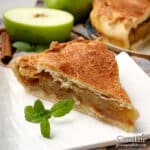 A slice of homemade apple pie on a white plate.