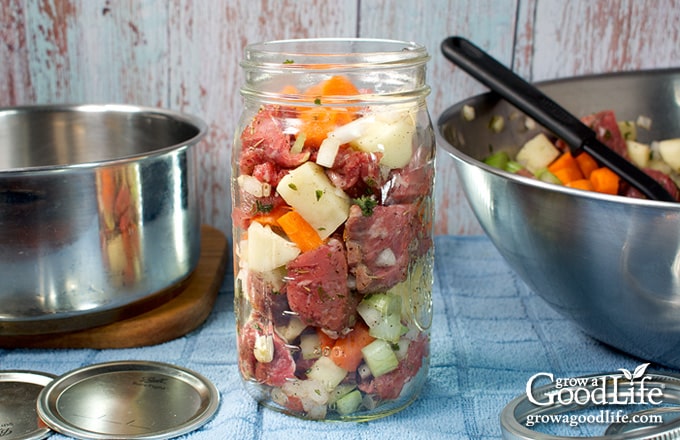 Filling a quart canning jar with beef pot roast ingredients for canning.