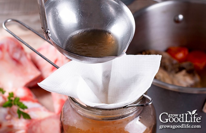 straining the beef stock through cheesecloth