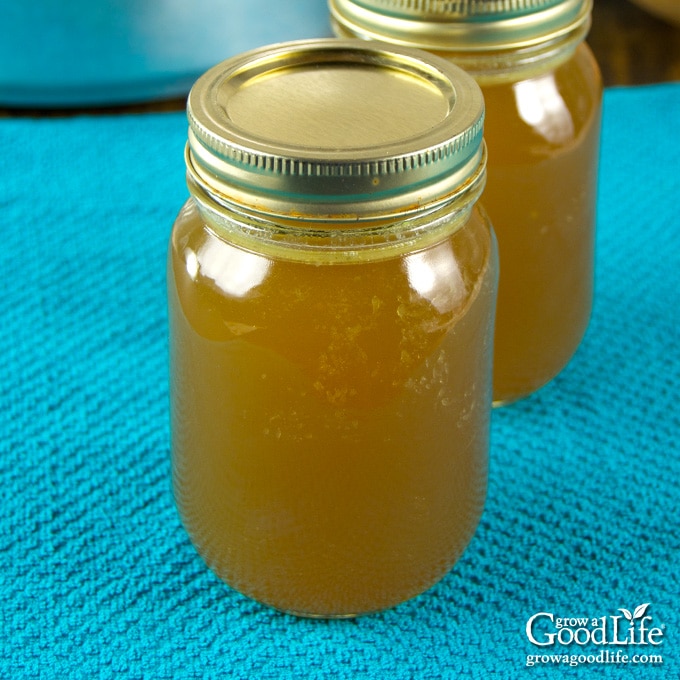 jars of home canned chicken stock on a teal towel