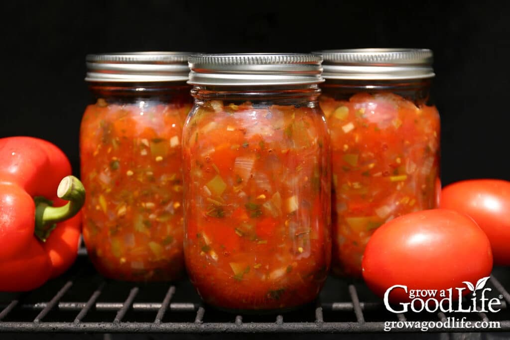 Pint jars of home canned fire roasted salsa on a grill grate.