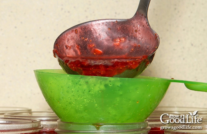 photo of a canning ladle and funnel adding cherry jam to a jar