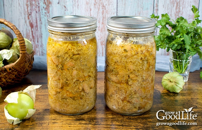 Two quart sized mason jars of home canned chicken chili verde on a table.