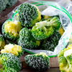 image of frozen broccoli in a freezer bag and scattered on a table