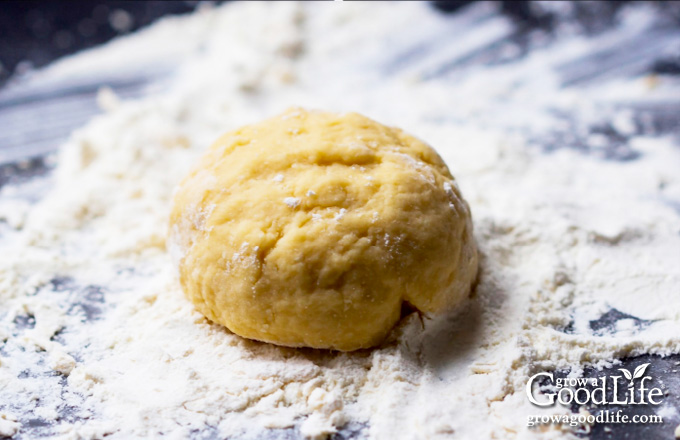 pasta dough formed into a ball on a lightly floured surface