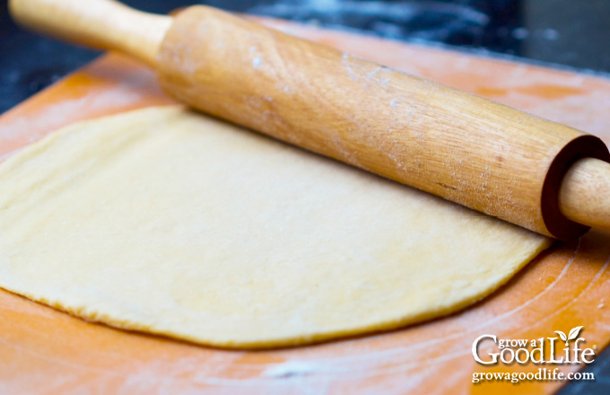 rolling out pasta dough on a floured surface