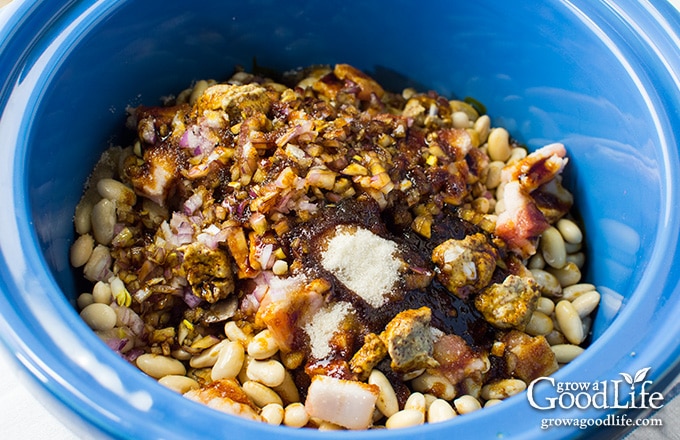 adding the ingredients for baked beans to the slow cooker crock