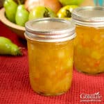 Jars of home canned green tomato piccalilli on a table.