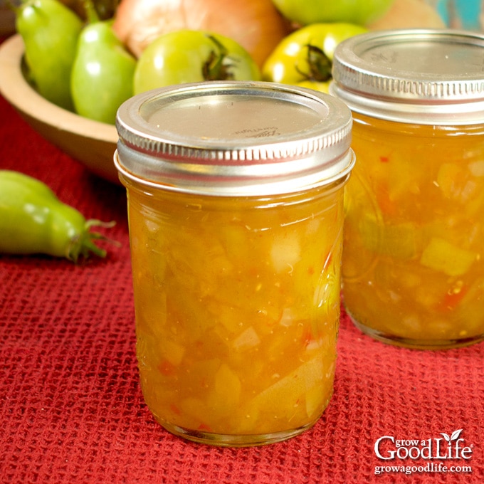 Jars of home canned green tomato piccalilli on a table.