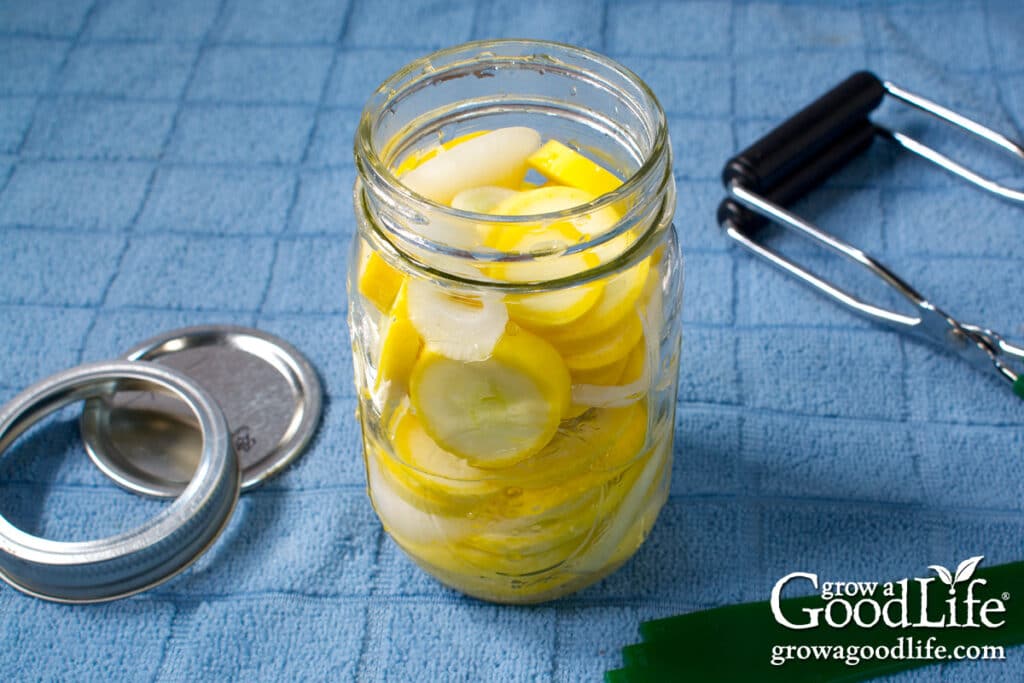 Filling a canning jar with yellow summer squash mix.