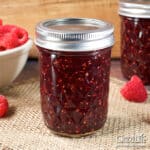 Jars of home canned raspberry jam on a table.