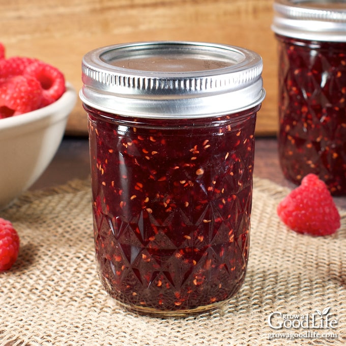 Jars of home canned raspberry jam on a table.