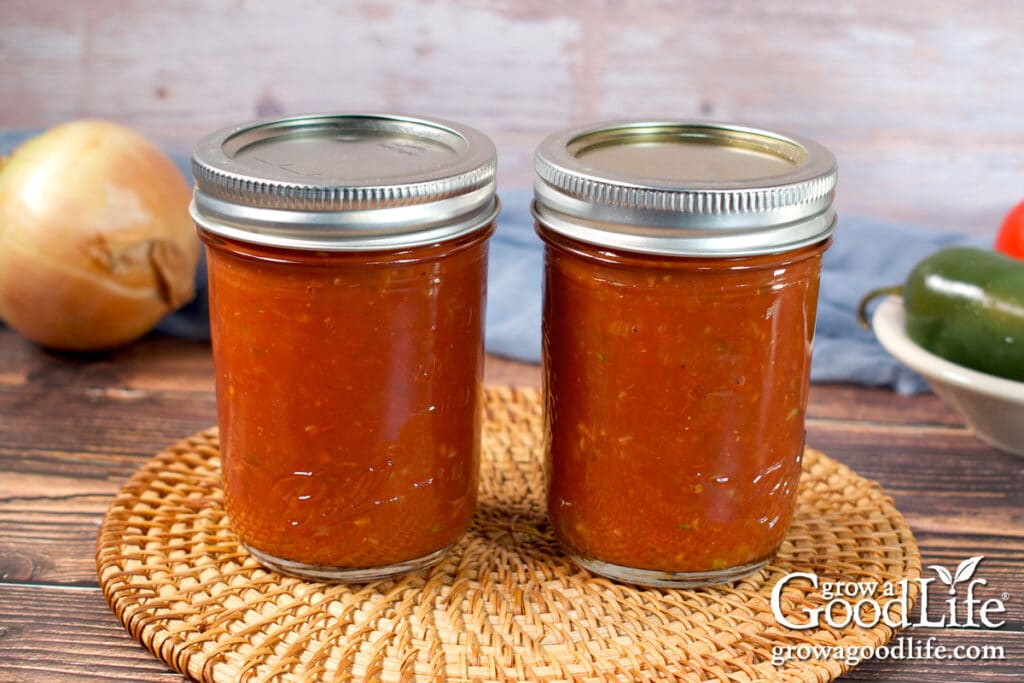 Two jars of home canned restaurant style salsa on a table.