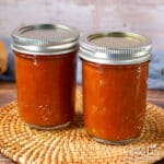 Jars of restaurant-style salsa on a table.