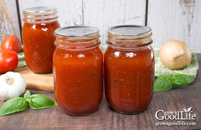 Jars of home canned roasted tomato soup on a table.