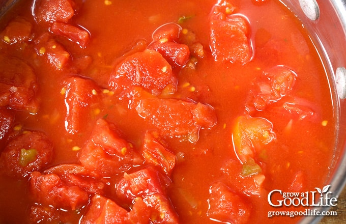 Stewed tomatoes summering in a large sauce pot.