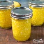 Jars of home canned yellow summer squash relish on a table.