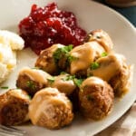 photo of a plate of Swedish meatballs, mashed potatoes, and cranberry sauce on a table