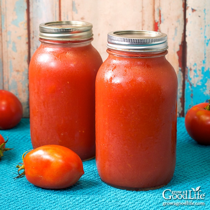 canning jars of tomato puree on a blue towel