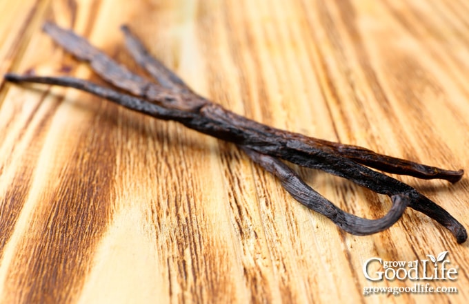 three vanilla bean pods on cutting board