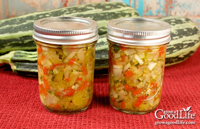 Jars of zucchini relish cooling on a red towel.